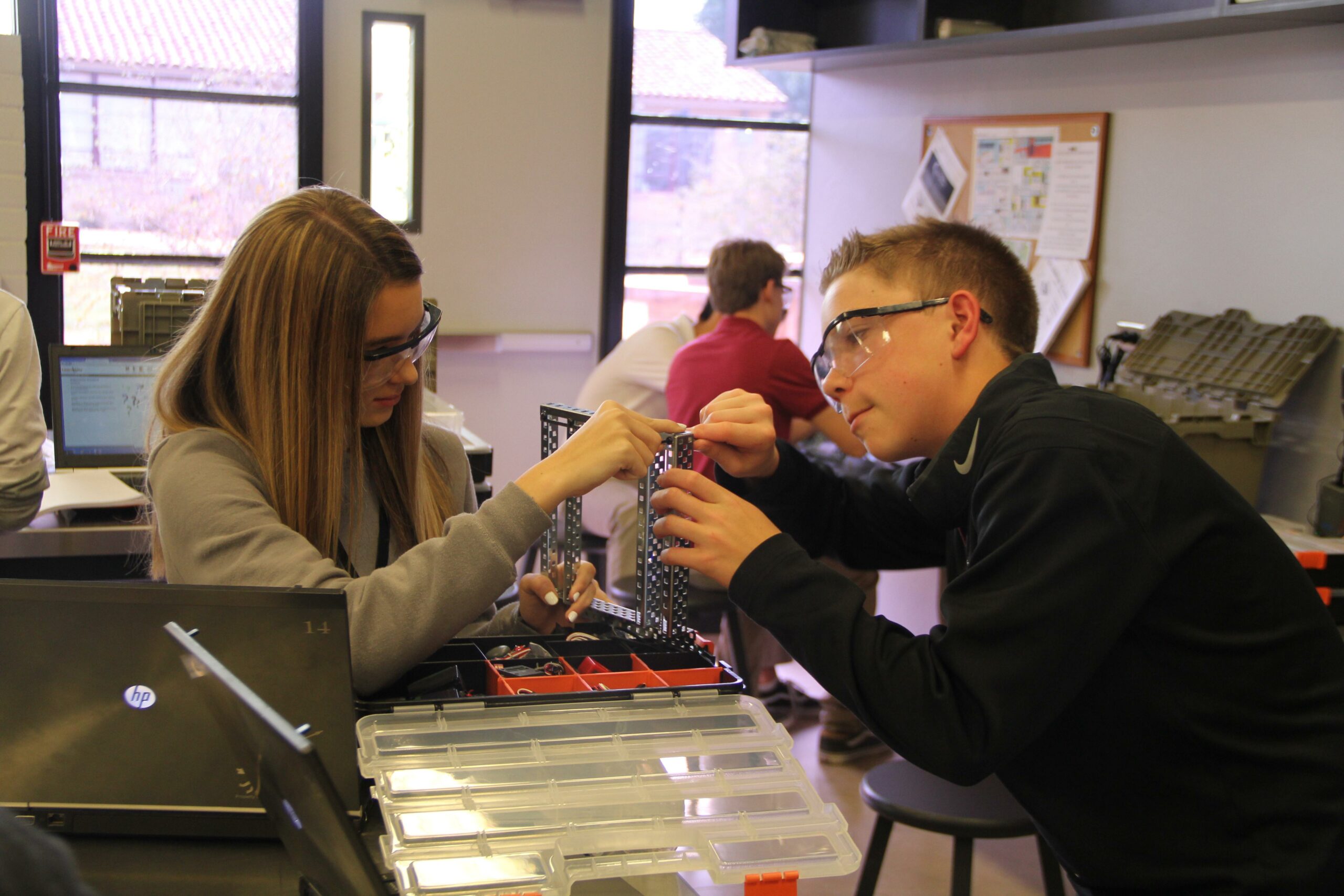 Students building a metal structure with safety glasses