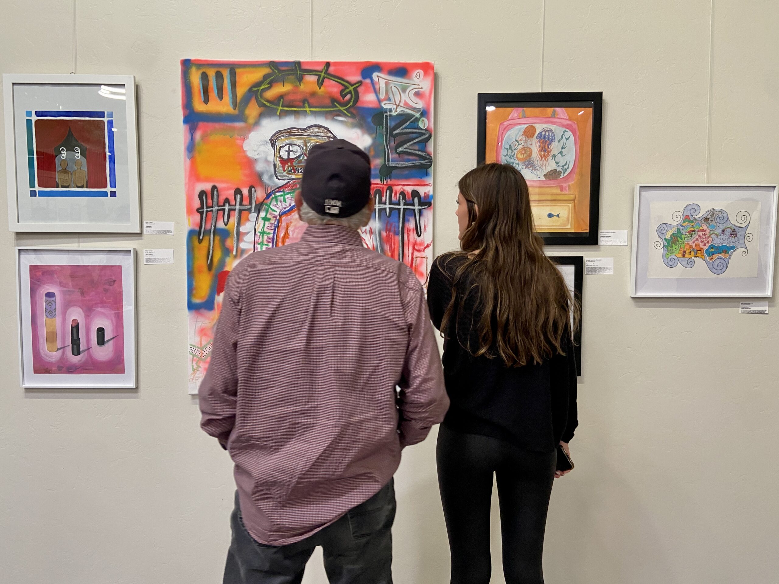 Student and grandparent looking at artwork hanging on the wall in the Stevens Art Gallery.